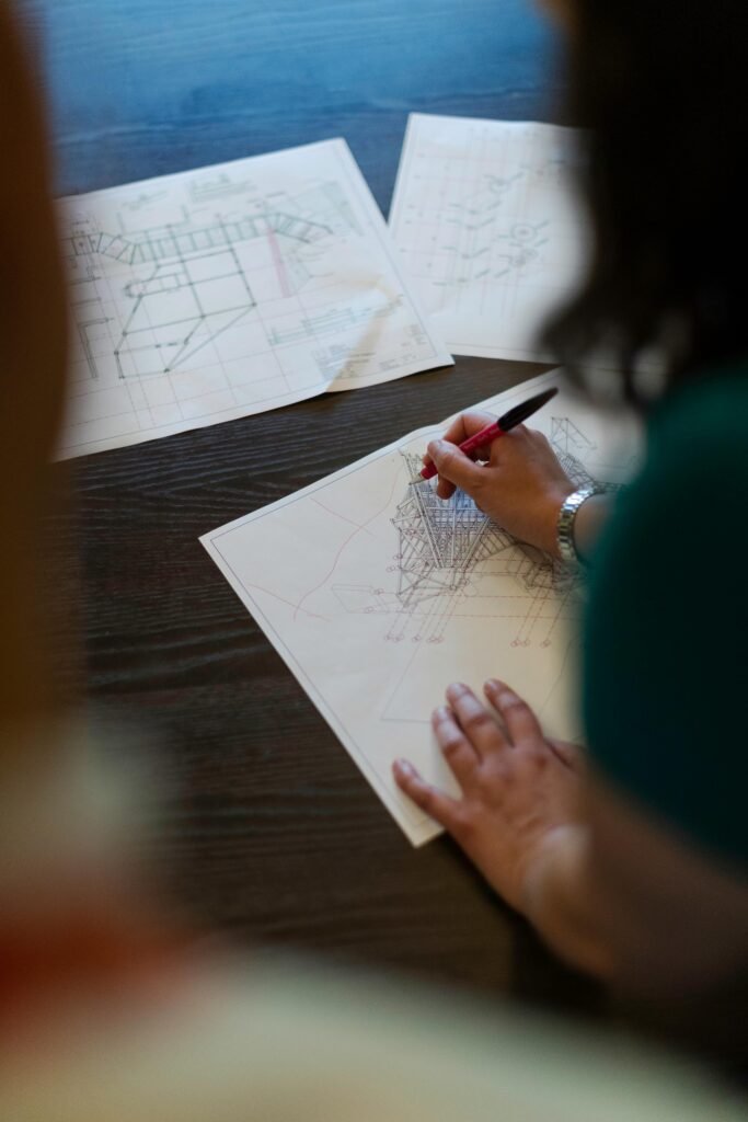 pexels-photo-3862377-3862377 Female engineer working on detailed architectural blueprints on a wooden desk.